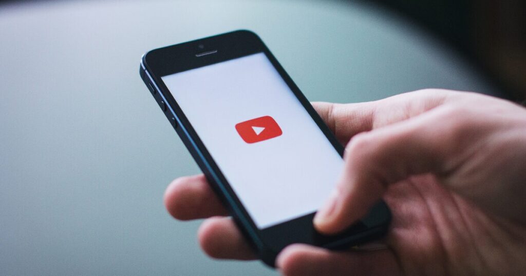 スマホでYouTubeアプリを開こうとしている手